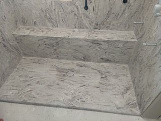 A shower stall with a marble floor and walls in a bathroom.