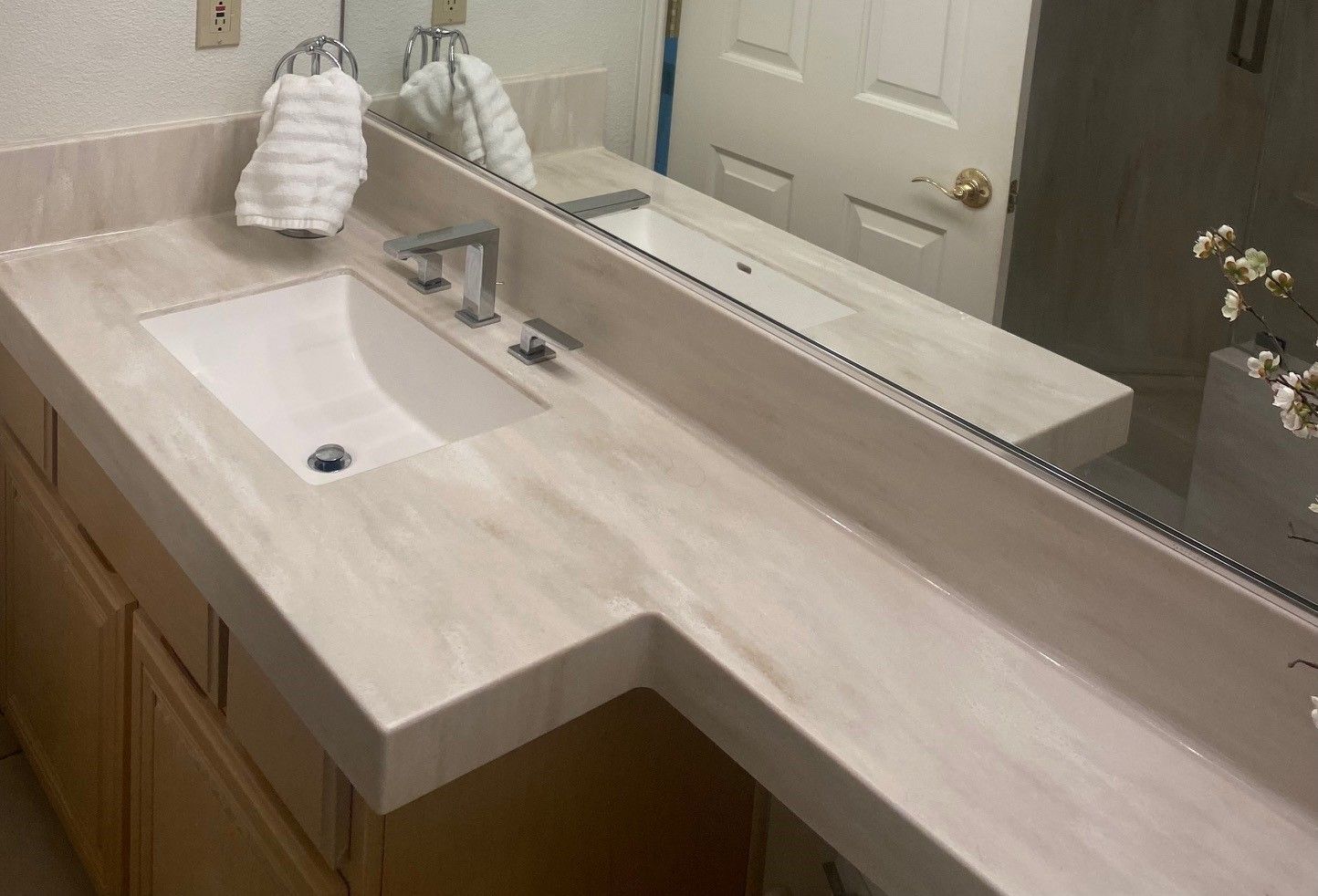 A bathroom with a sink , mirror and cabinets.