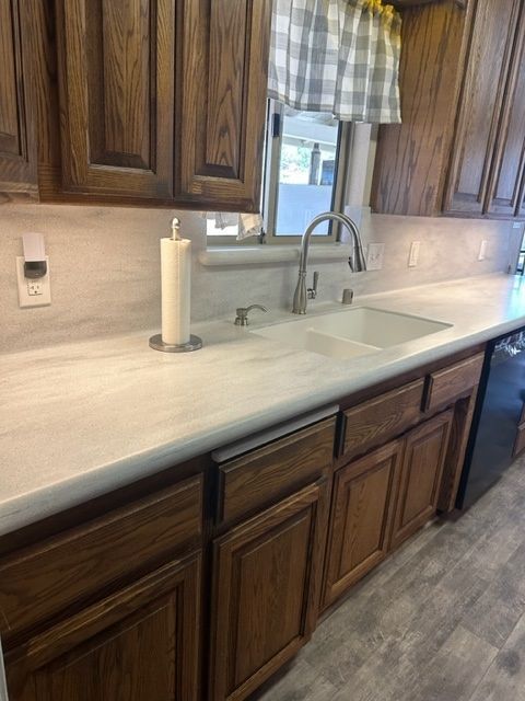 A kitchen with wooden cabinets , a sink , and a paper towel holder.