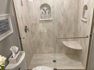 A bathroom with a toilet and a walk in shower.