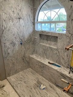 A bathroom with marble walls and a window.