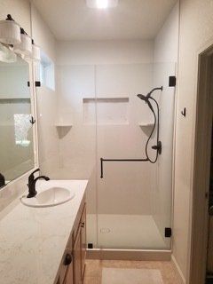 A bathroom with a walk in shower and a sink.