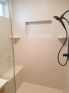 A bathroom with a walk in shower with a glass door and a shower head.