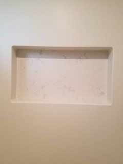 A white wall with a shelf in the middle of it.