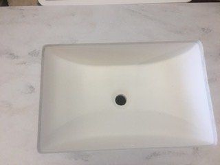 A white sink is sitting on top of a white counter.