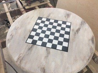 A round table with a checkered chess board on top of it.
