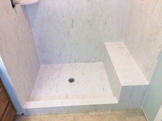 A bathroom with a walk in shower with a bench.