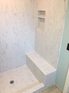 A bathroom with a walk in shower and a bench.