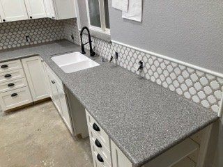 A kitchen with white cabinets , granite counter tops , and a sink.