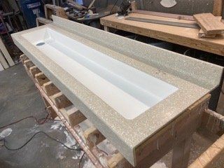 A long sink is sitting on top of a wooden table.