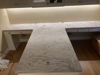 A kitchen with a granite counter top and a desk.