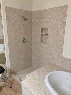 A bathroom with a walk in shower and a sink.