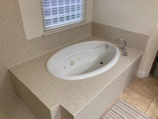 A bathtub is sitting on top of a counter in a bathroom next to a window.