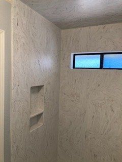 A bathroom with marble walls and a window.