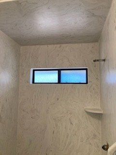 A shower with a window and a shelf in it.