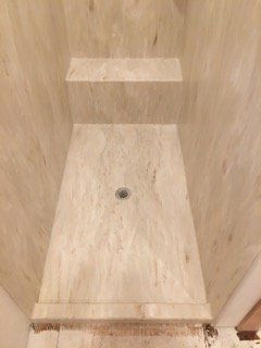 A shower stall with a marble floor and steps in a bathroom.