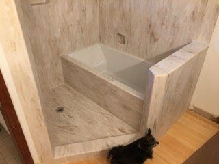 A cat is standing next to a bathtub in a bathroom.