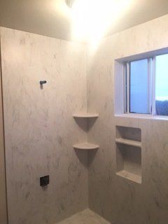 A bathroom with a walk in shower and a window.