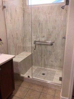 A bathroom with a walk in shower and a sink.