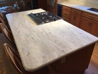 A kitchen with a large island with a stove top oven on it.