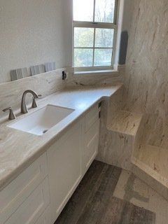 A bathroom with a sink , shower and window.