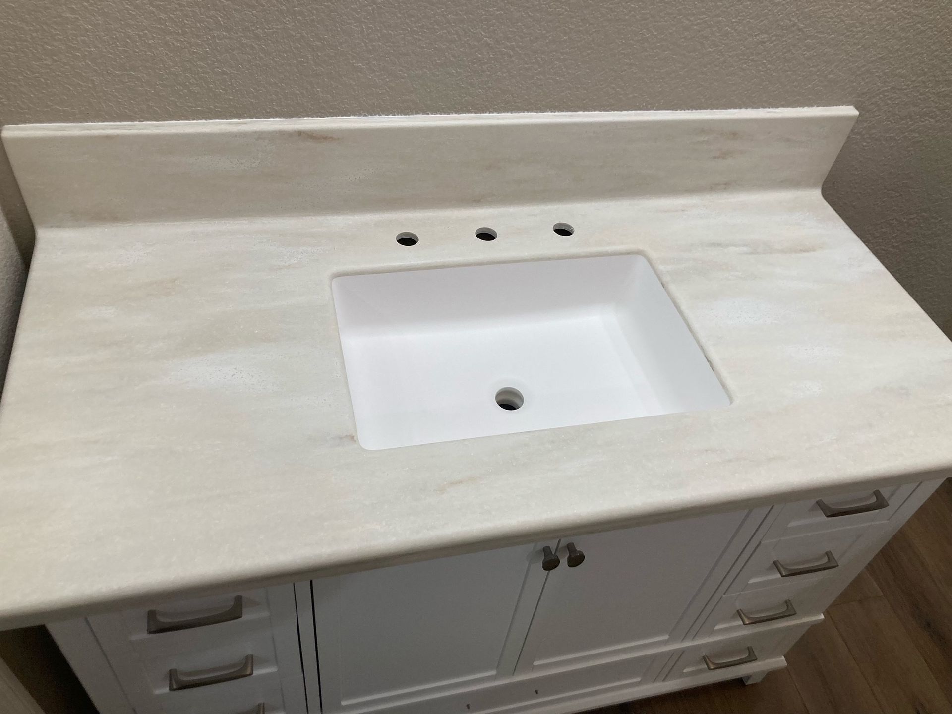 A bathroom vanity with a white sink and a white counter top.