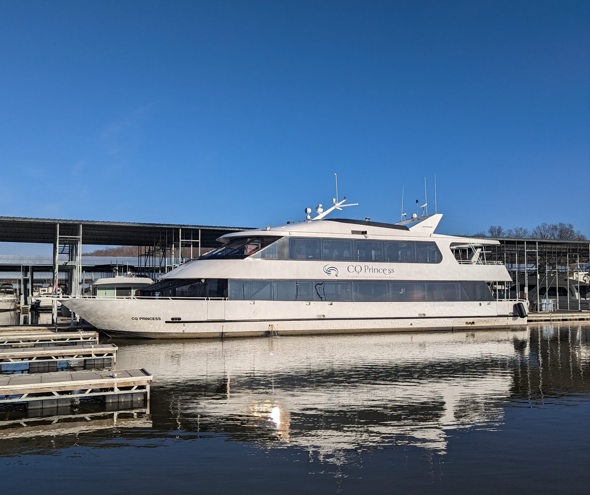 A large white boat is docked at a marina.