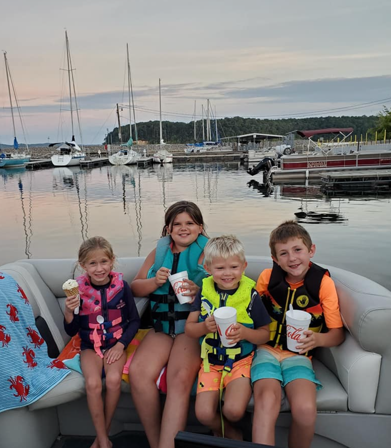 A group of children are sitting on a boat eating ice cream.