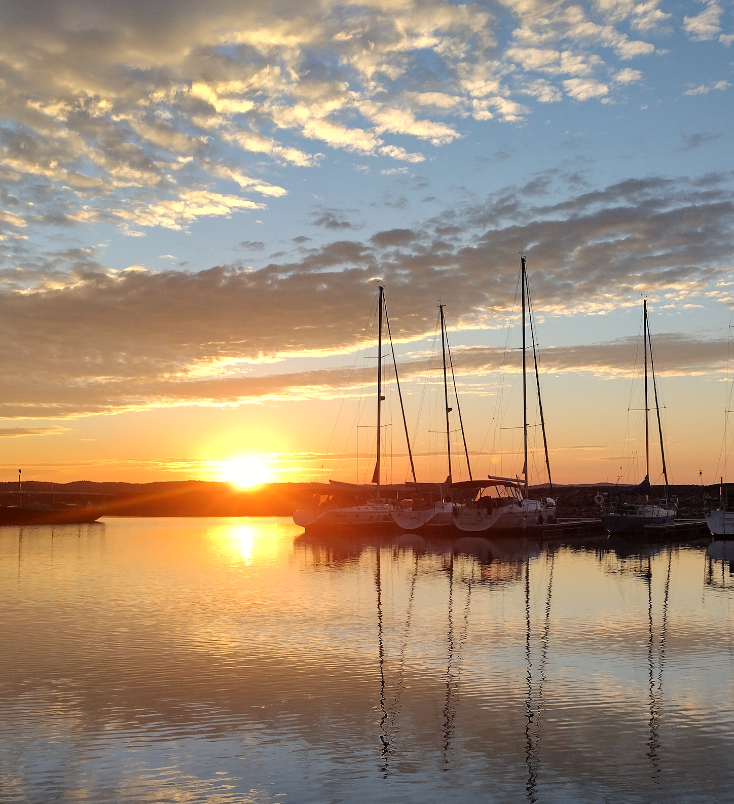 Boats are docked in a harbor at sunset