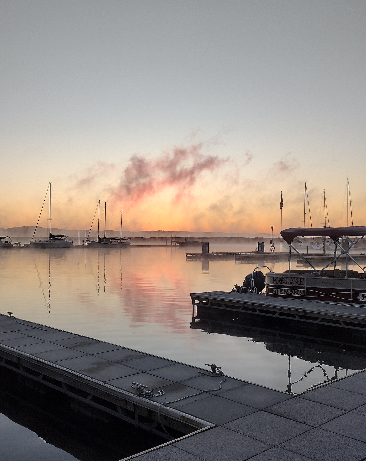 A sunset over a body of water with boats docked