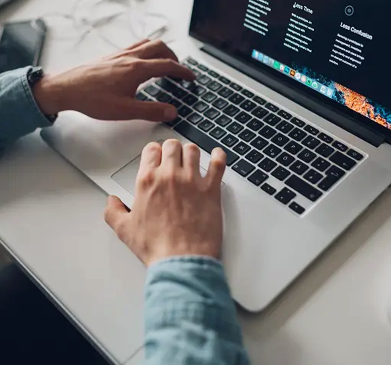A row of boats are docked at a marina on a river.