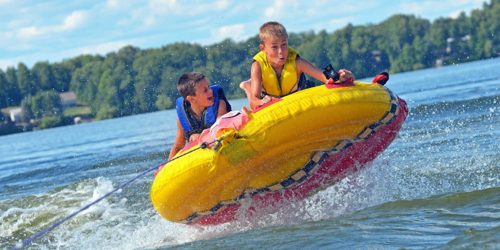 Two young boys are being towed by a boat on a lake.