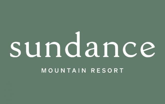 Three cars are parked in front of a brick building.