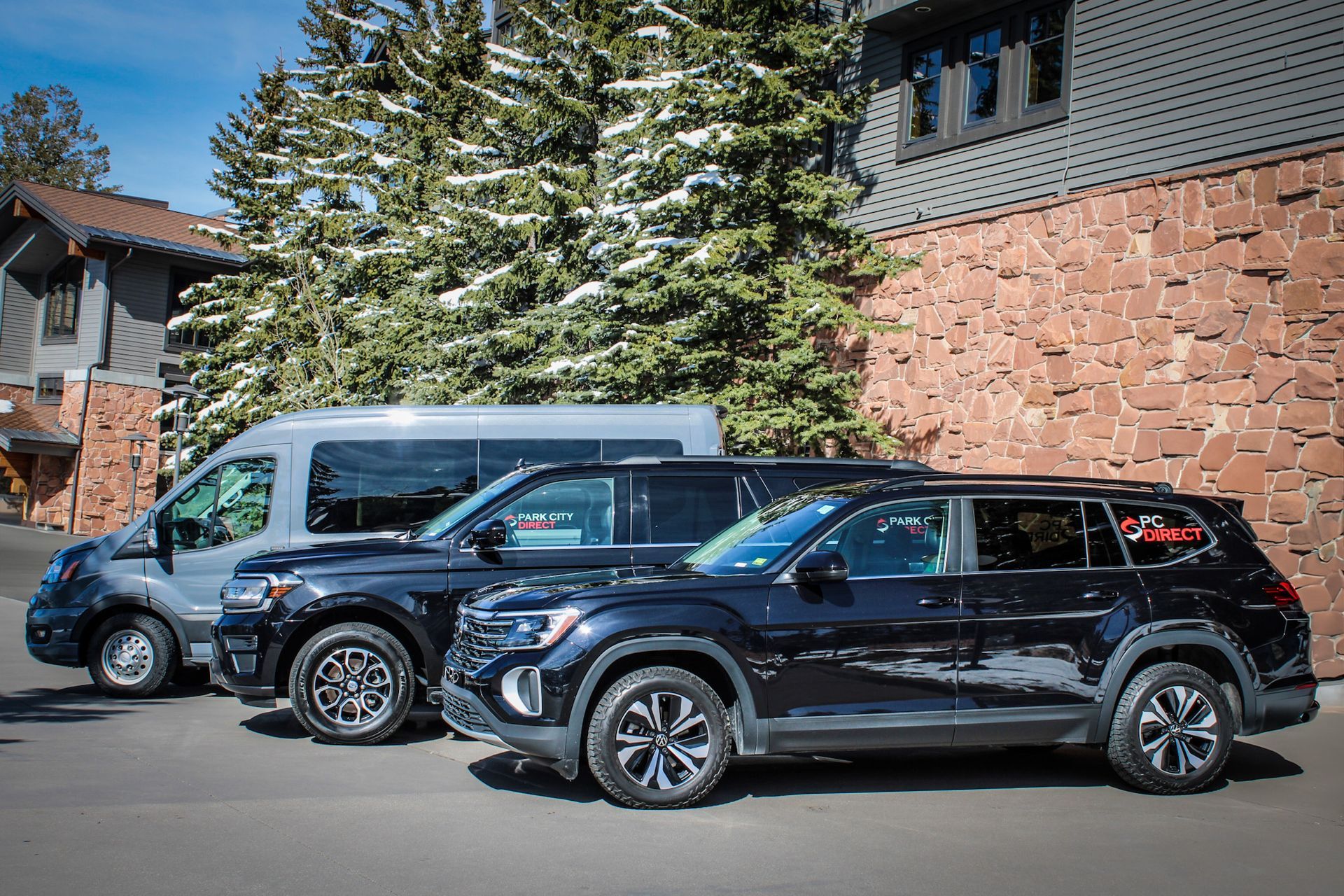 Three cars are parked in front of a brick building.