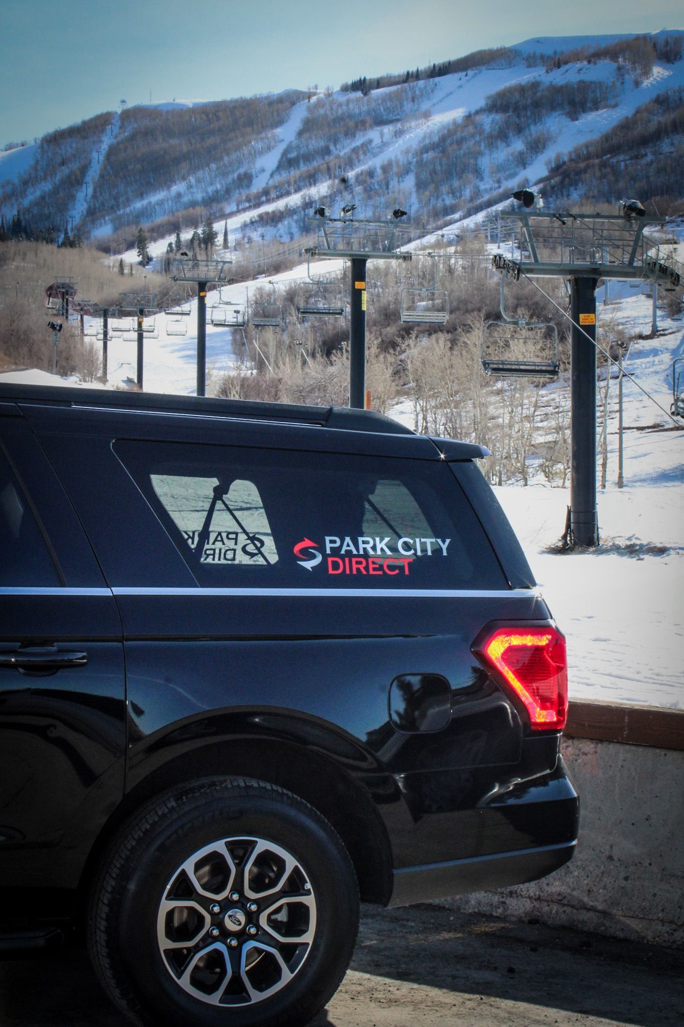 A black suv is parked in front of a snowy mountain.
