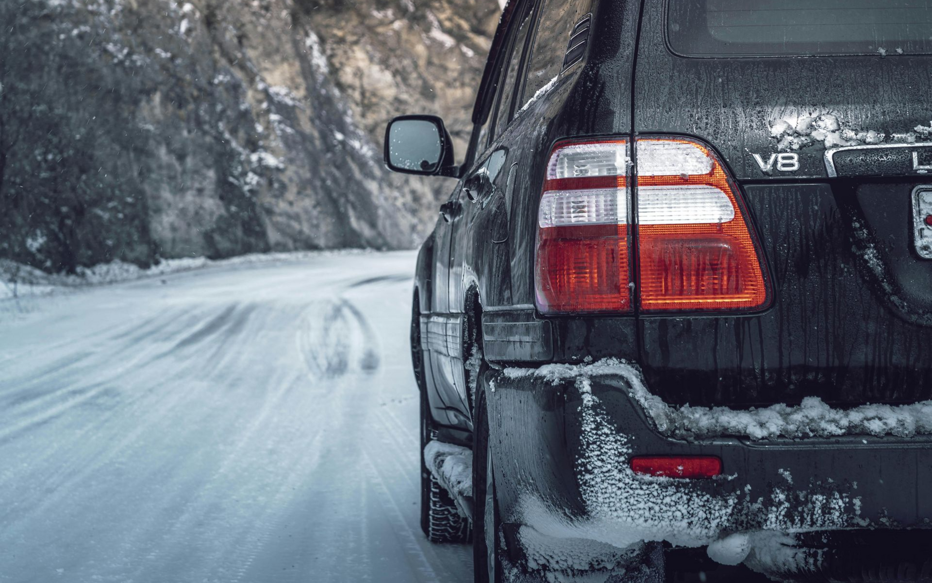 Black SUV on a snowy road in a mountain setting, with ice and snow visible.
