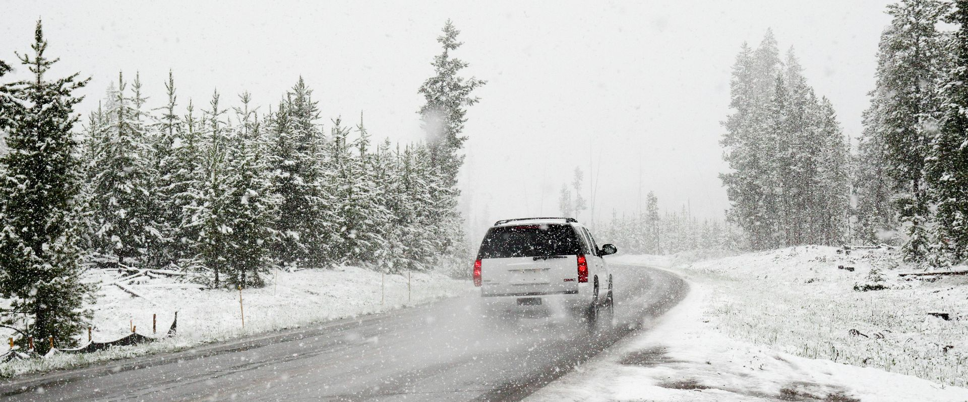 Three cars are parked in front of a brick building.