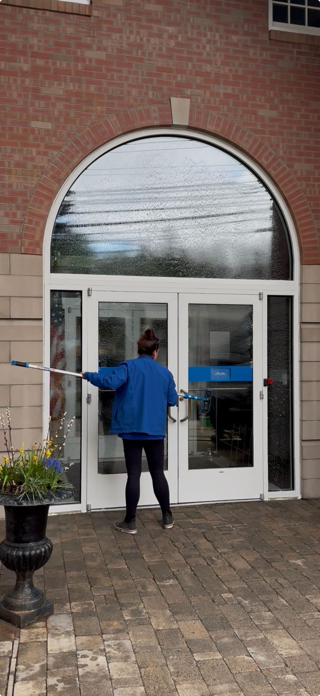 A mint green structure with a stone basin and faucet, seen through a glass storefront with a small heart decal.