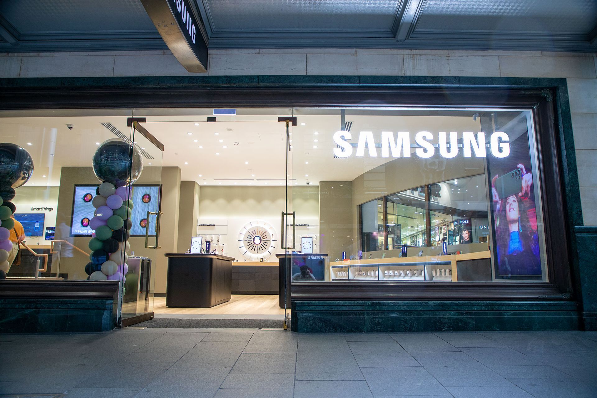 Samsung store exterior with awning, display windows, and people on sidewalk.