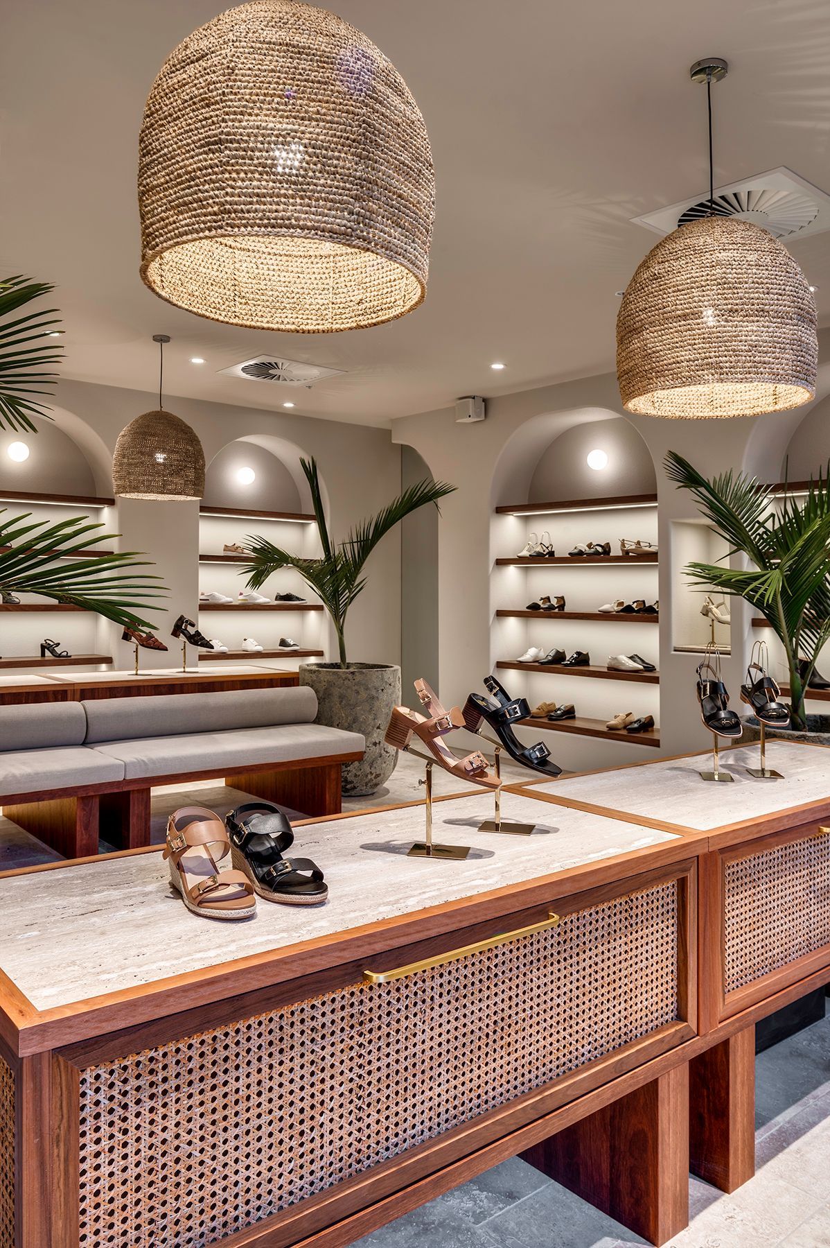 Shoe store interior with woven light fixtures, built-in shelving, and wooden display tables.