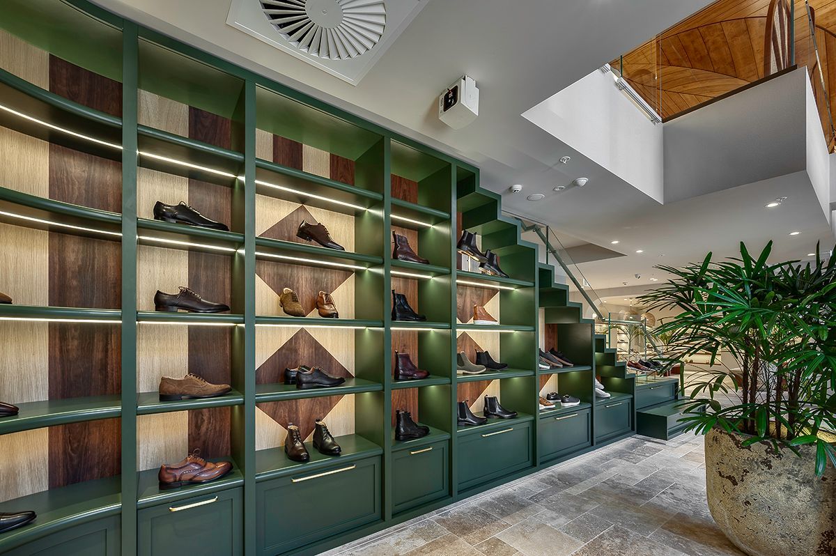 Shoe display in a store with green shelves, wood accents, and steps leading upward.