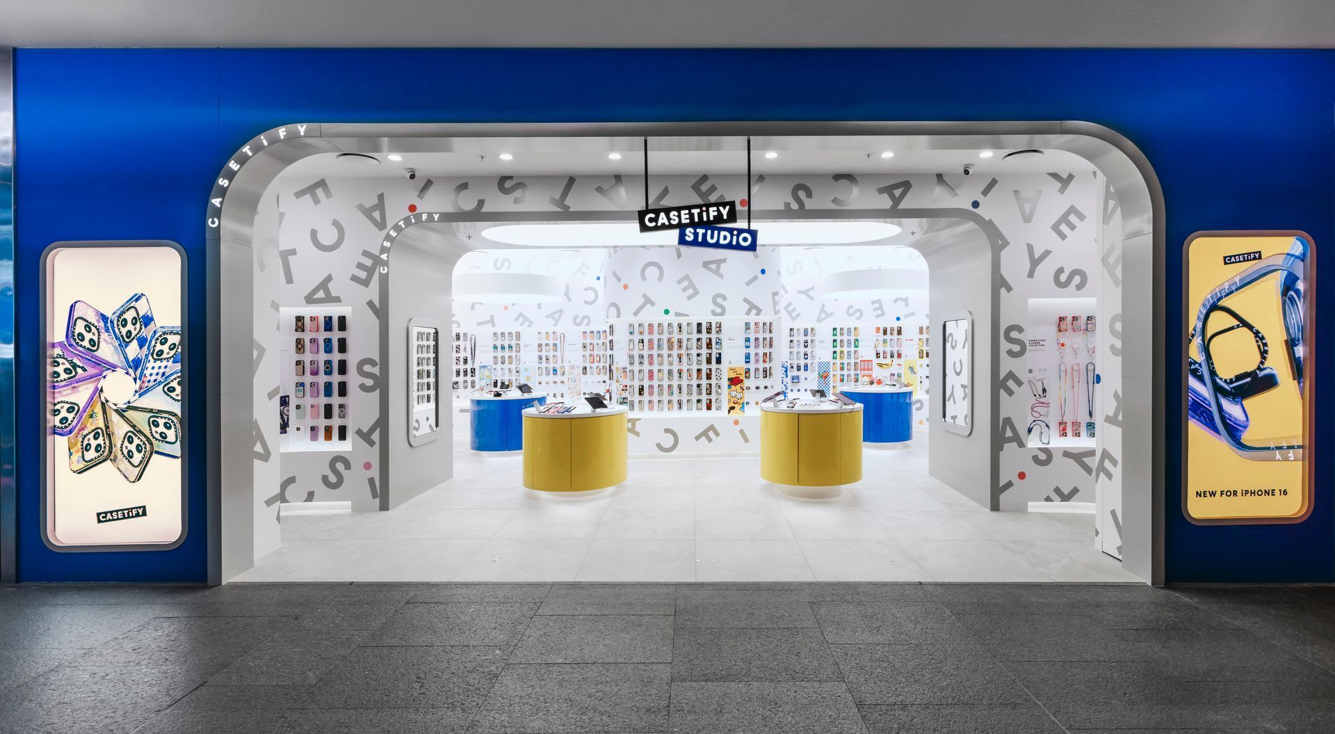 Storefront with a blue archway entrance, yellow display tables, and white shelves with colorful merchandise.