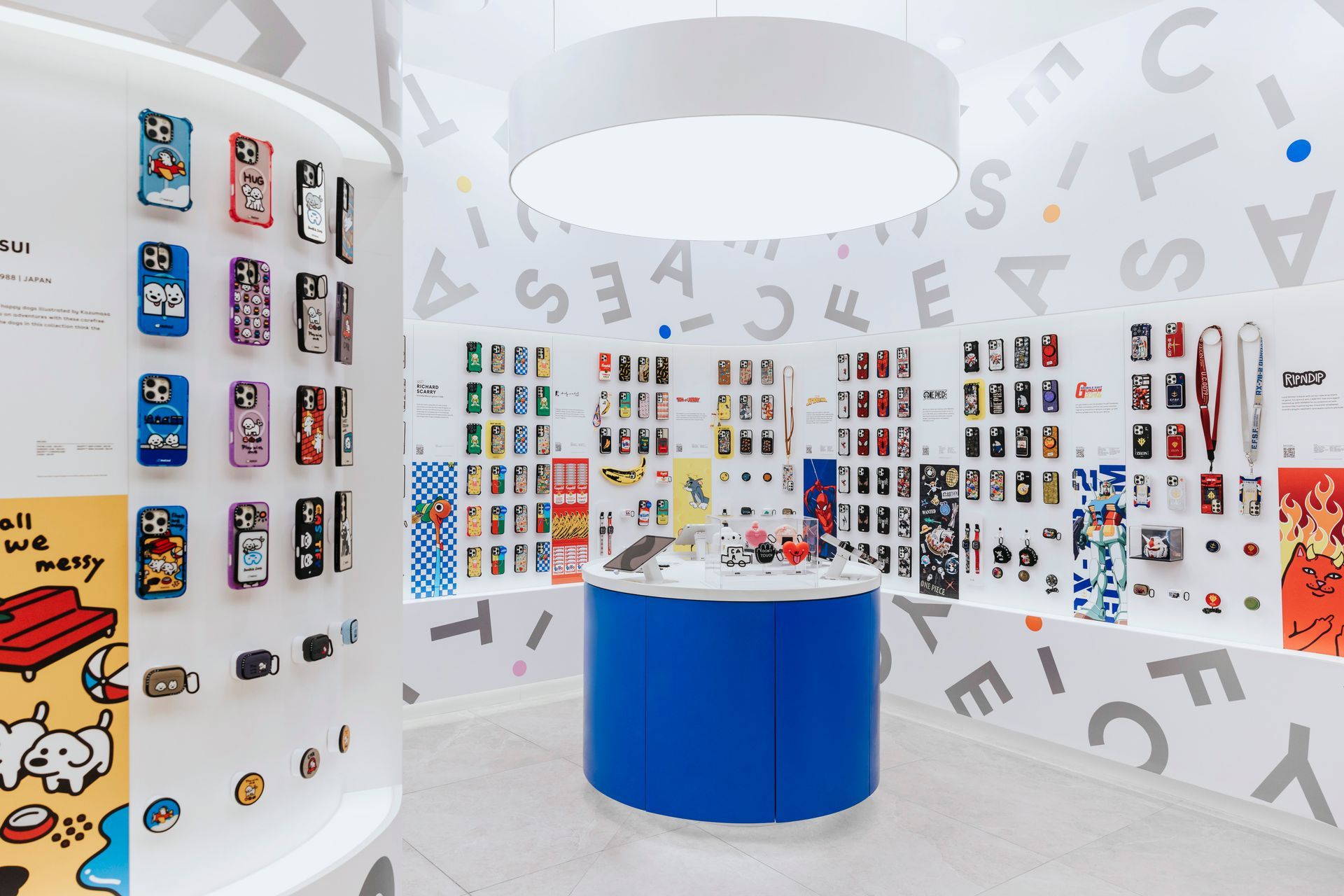 Phone case display in a white room with a blue central counter and a large circular light fixture.