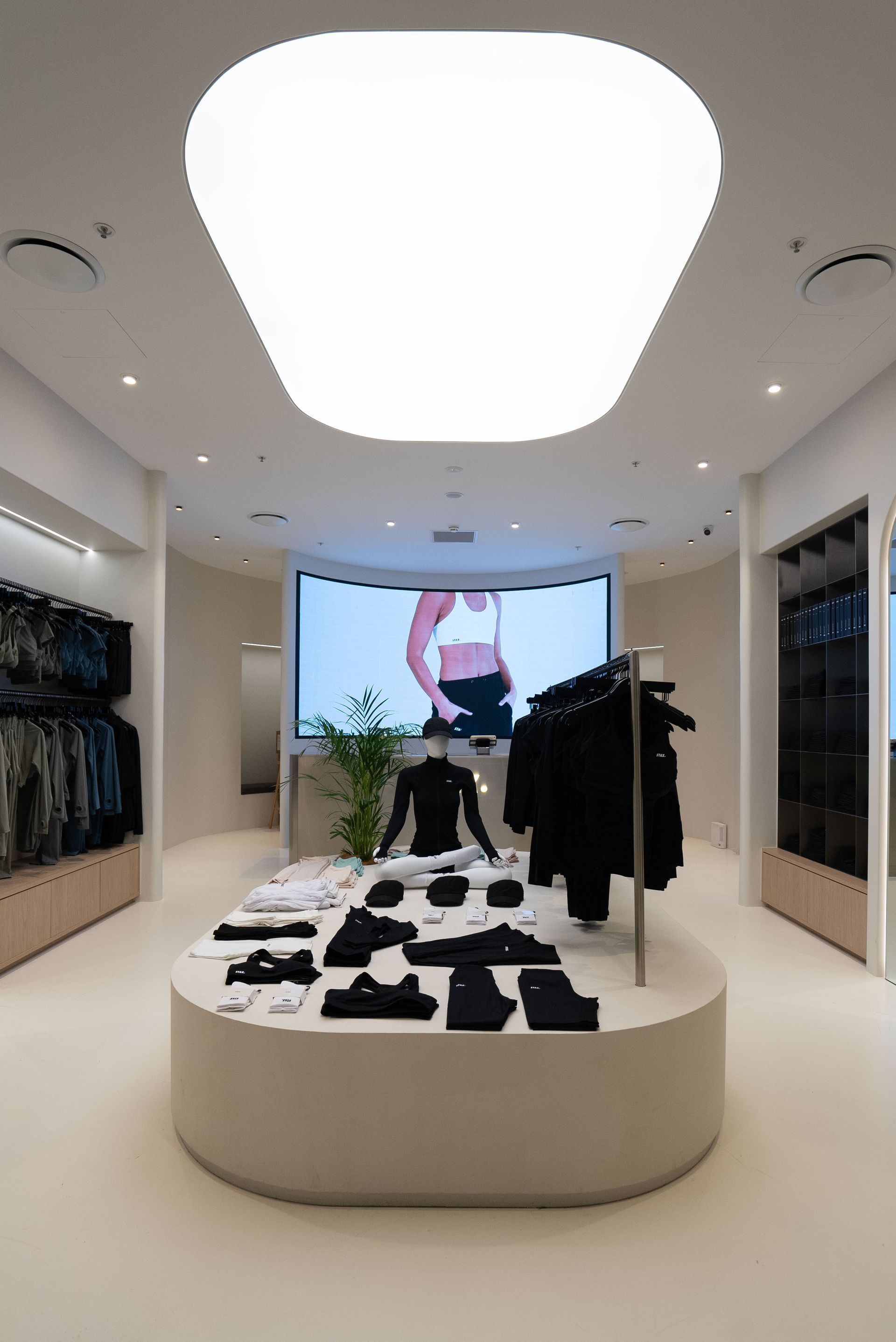 Clothing store interior with white walls, displays, and a large central counter.