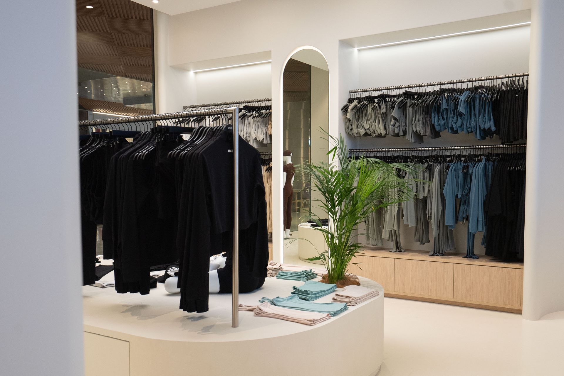 Clothing store interior with racks of clothes and a central display.