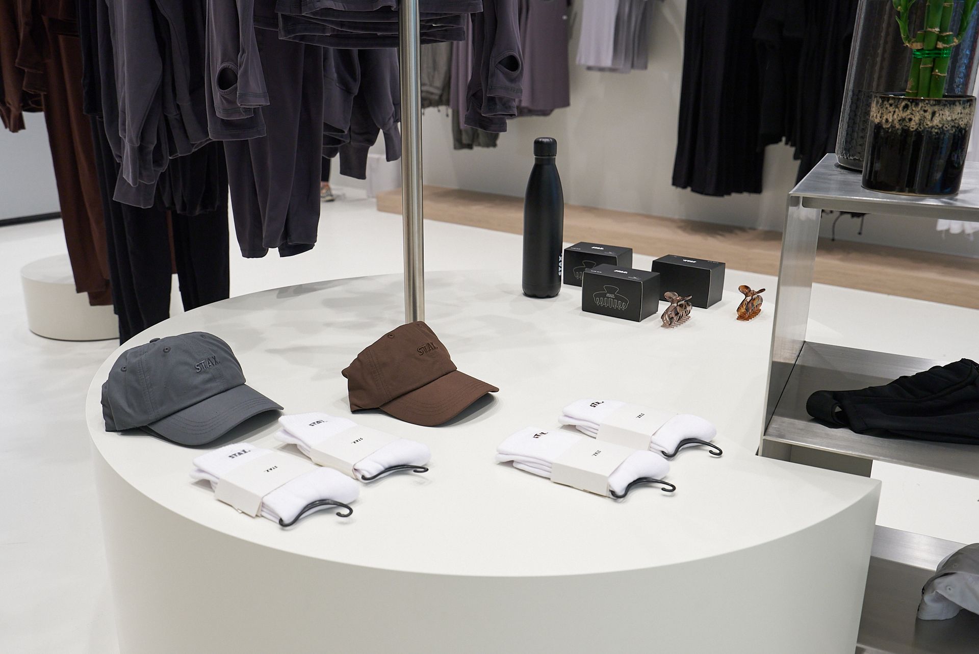 A retail display with clothing and accessories on a round white counter.