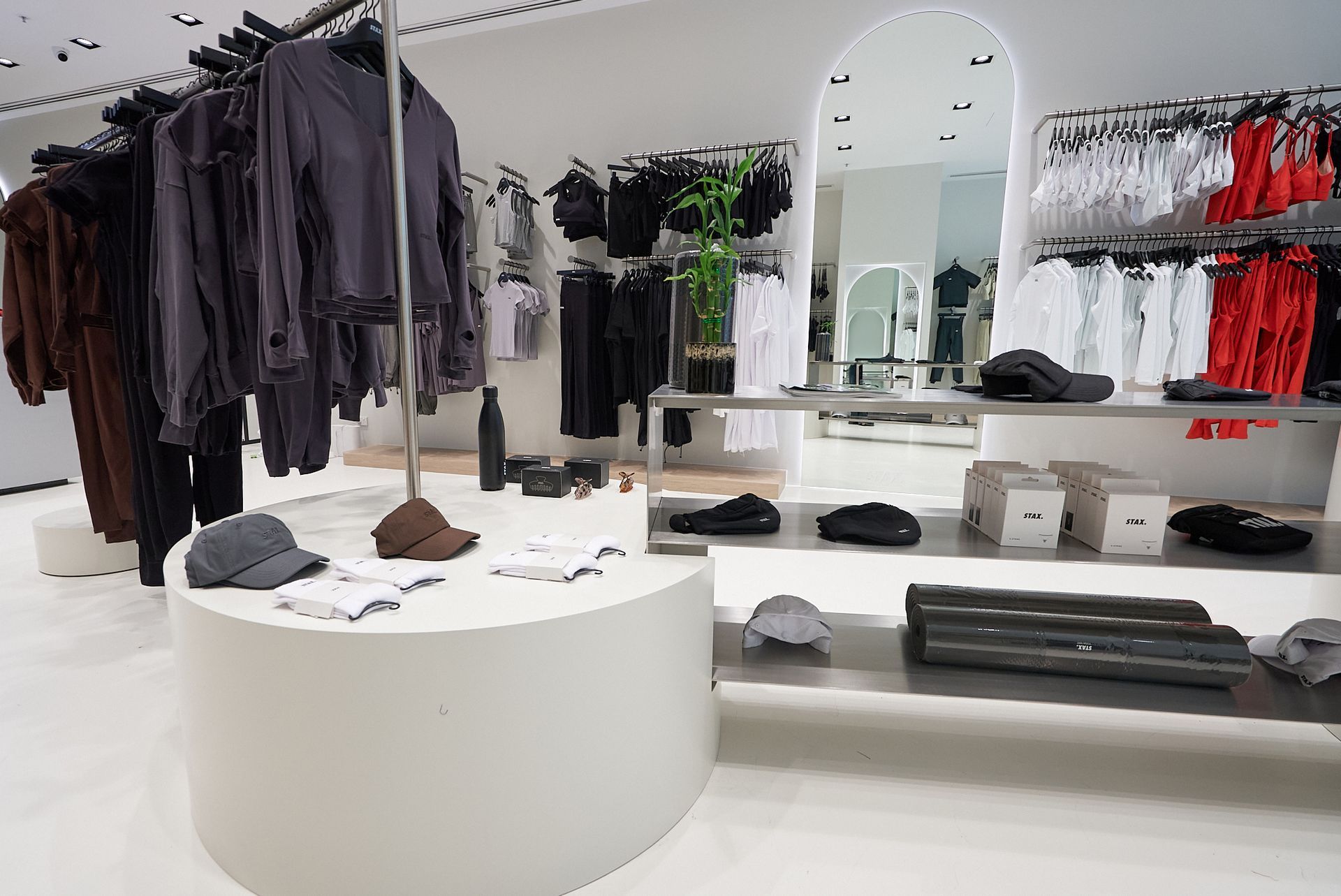 Clothing store interior with racks of clothes and display tables. Neutral color scheme, modern design.