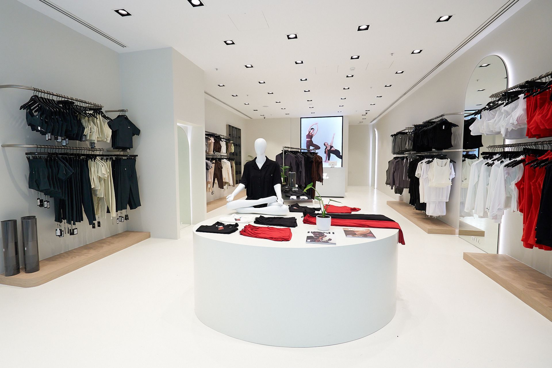 Modern clothing store interior with white walls, displays, and racks of apparel.