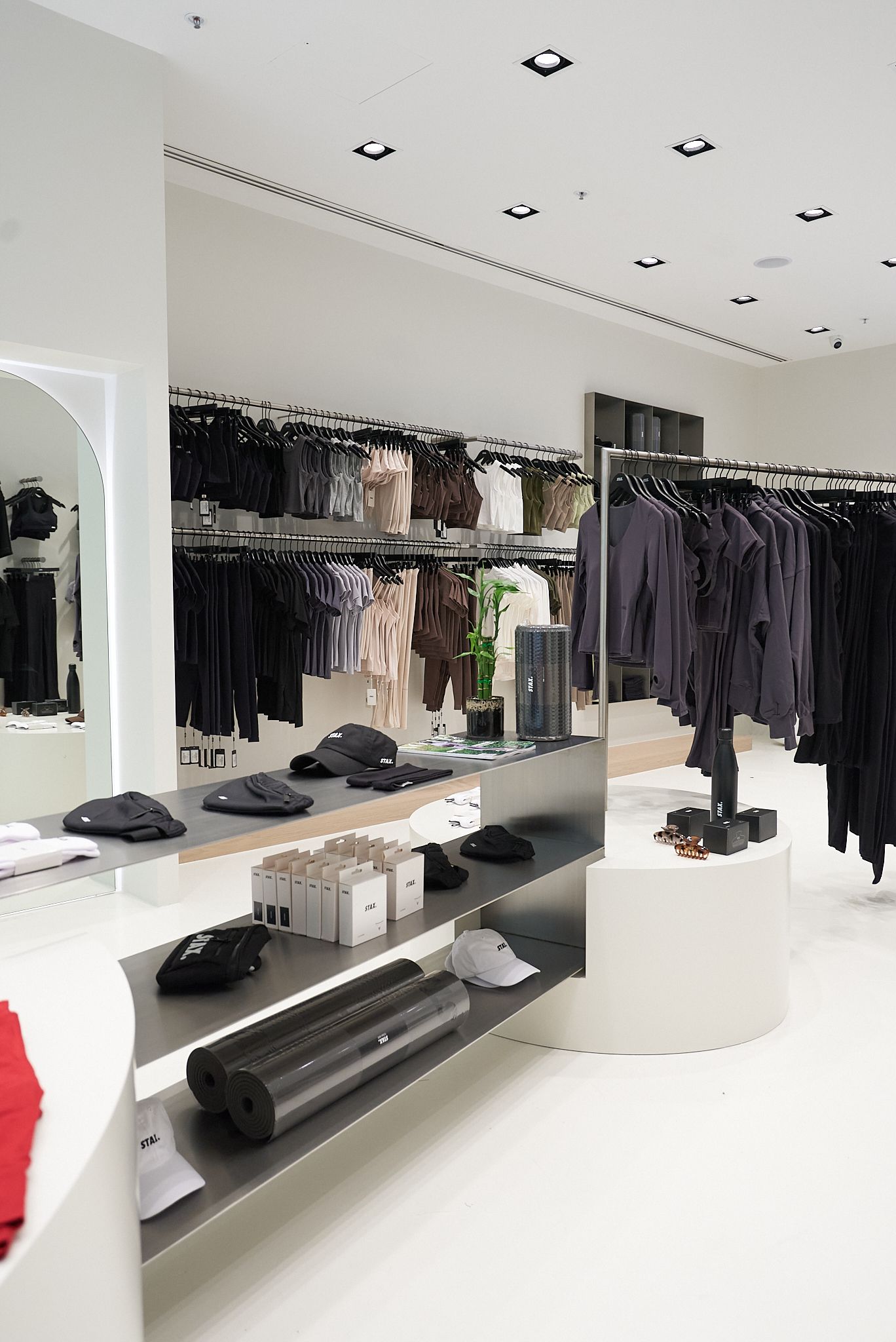 Clothing store interior with white walls, displays of black and neutral-colored clothing.