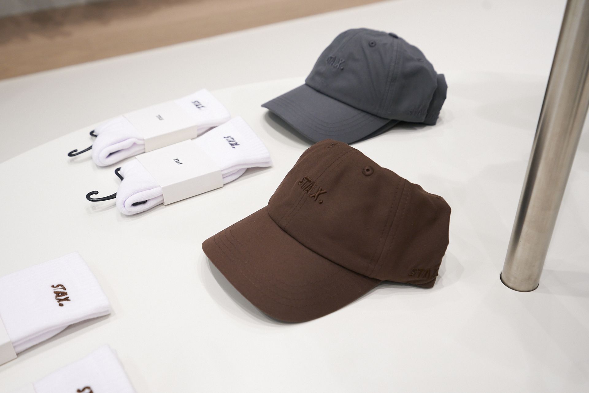 Brown and gray baseball caps on a white table with white socks.